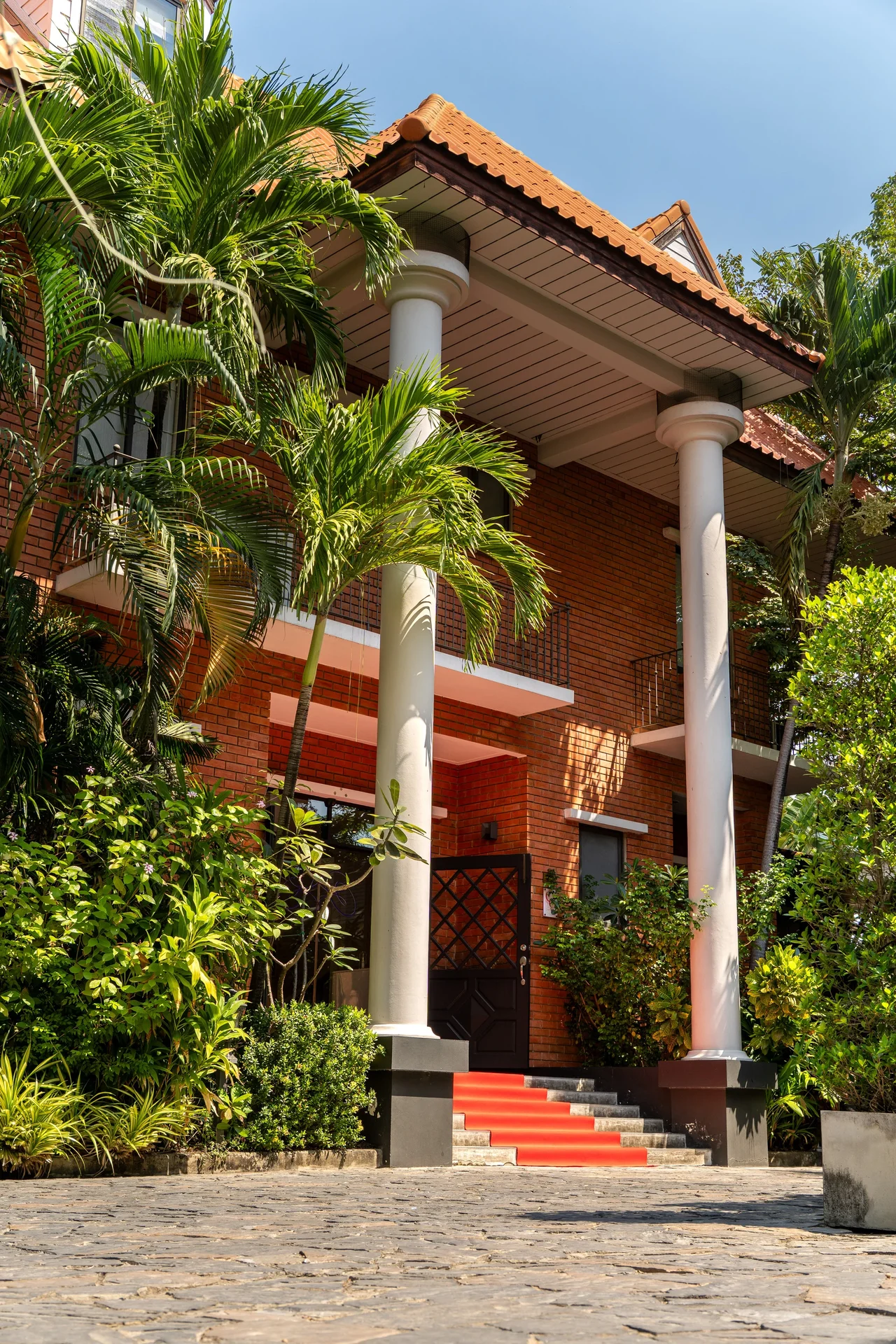 SÉREN Le Moment exterior with white columns, tropical greenery and the entrance steps